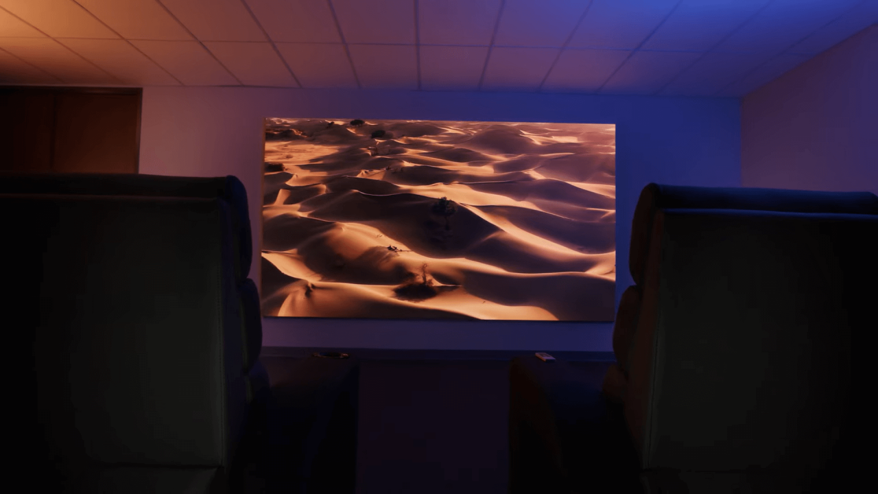 Ein vollständig abgedunkeltes Heimkino mit Kinosesseln und einer Wüstenprojektion, bei dem im Gegensatz zum hellen Wohnzimmer bereits niedrigere, aber verlässliche ANSI-Lumen-Werte für ein perfektes Seherlebnis ausreichen.