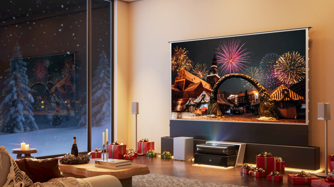 A cozy living room decorated for Christmas featuring a large projection screen displaying bright fireworks, powered by an ultra-short-throw laser TV projector placed on a low media console.