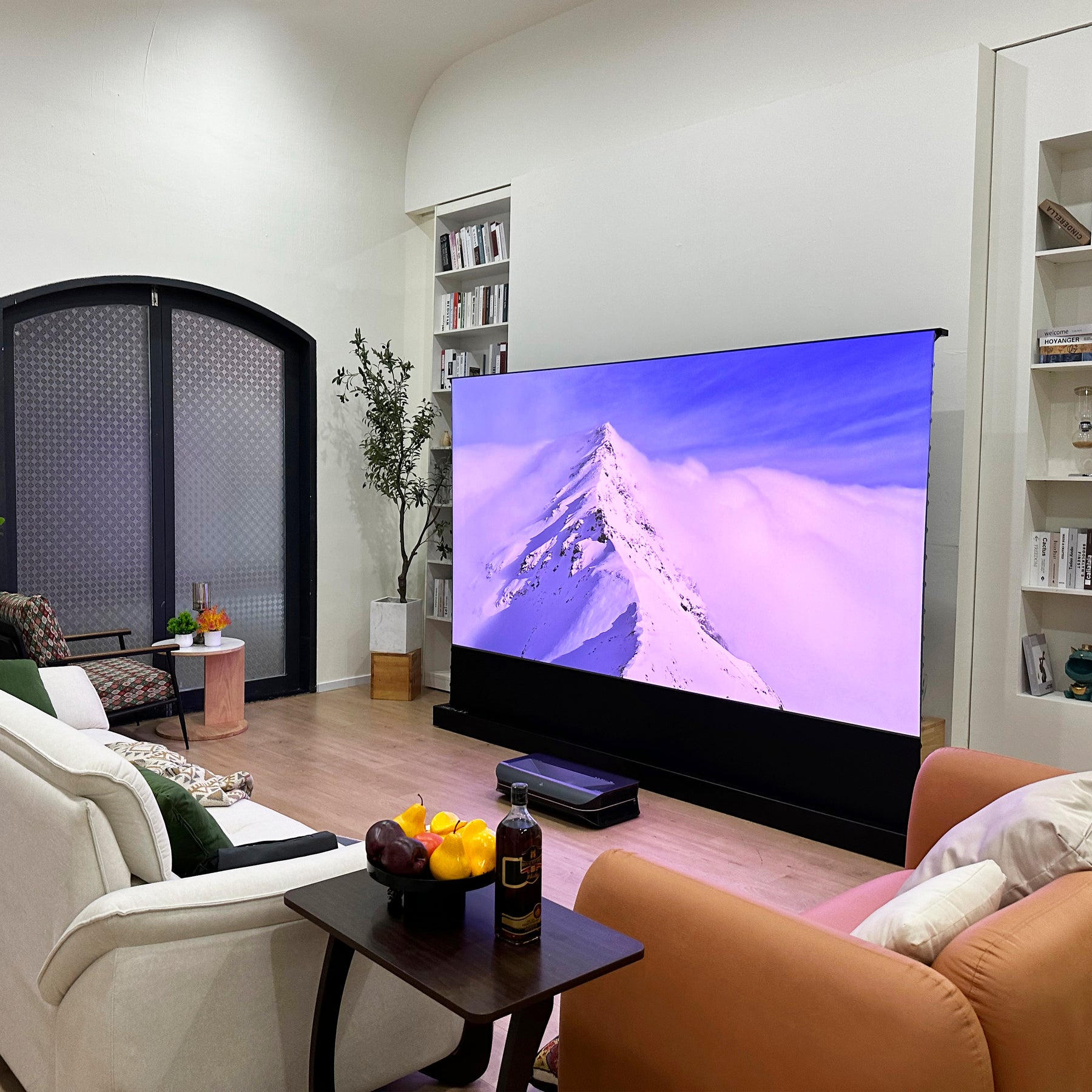 AWOL Vision Cinematic+ elektrische beamer leinwand im Wohnzimmer mit Bergpanorama in 4K Qualität.